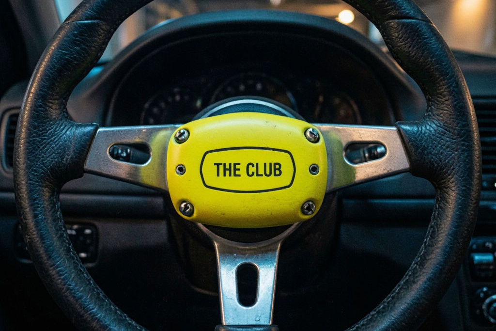 Желтый металлический замок The Club на рулевом колесе автомобиля в паркинге