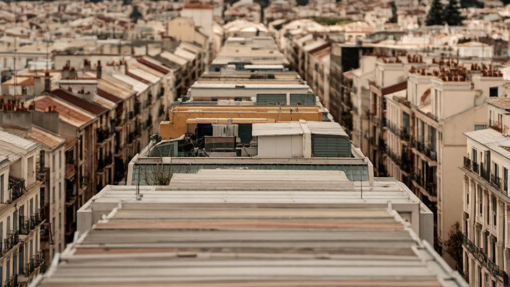 Высокий ракурс на кровли города и далекие холмы под облачным небом